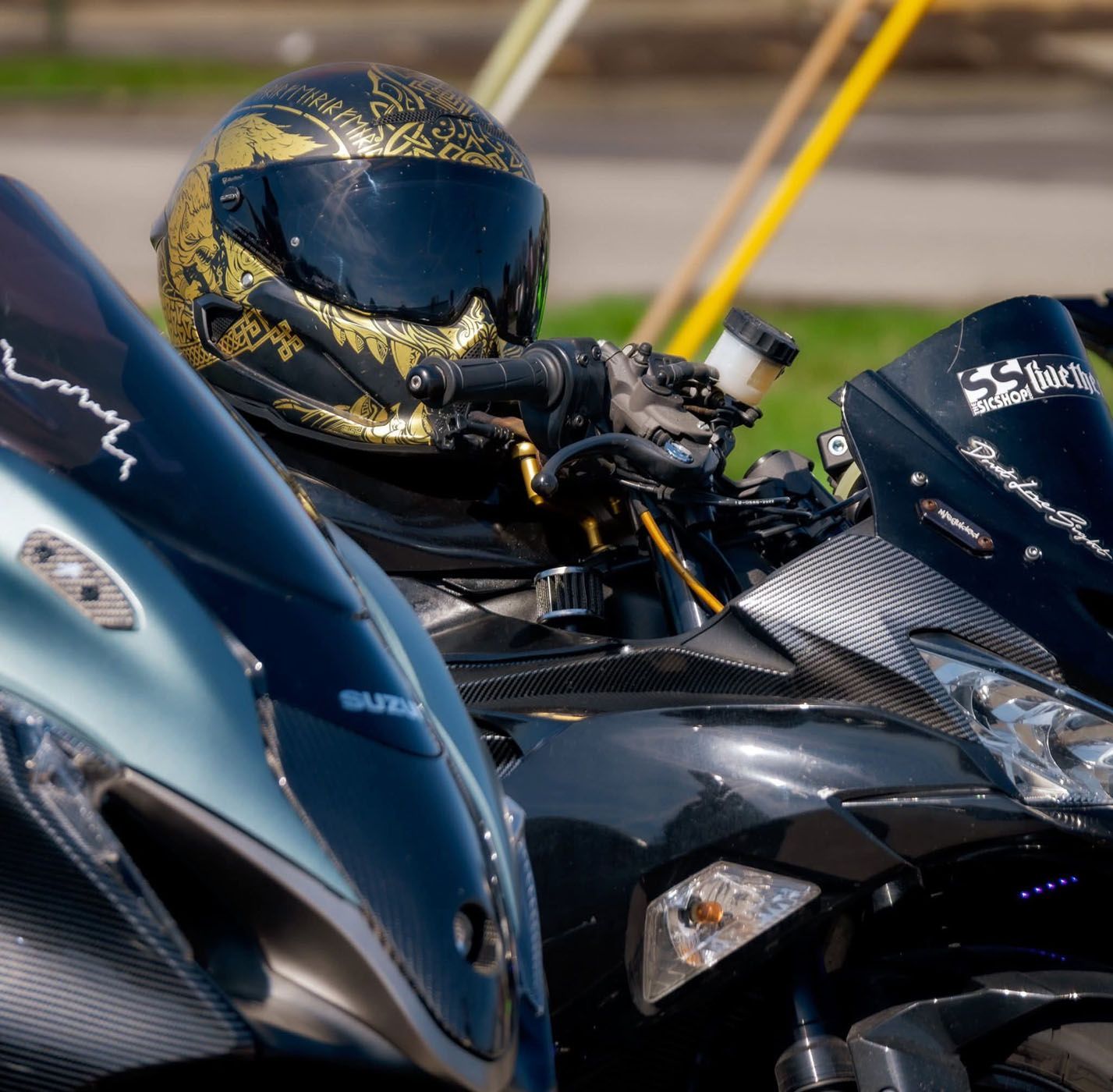 Motorcyclist in a black-and-gold helmet riding a black sport bike