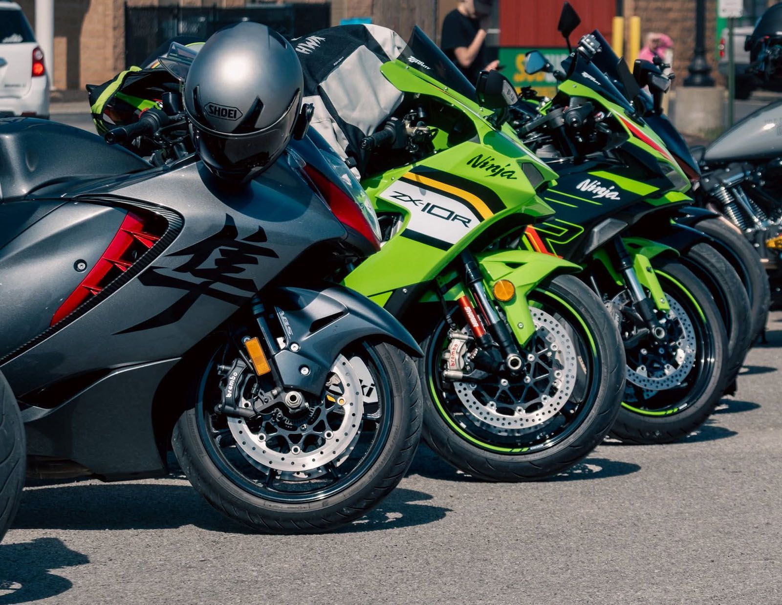 Row of sport motorcycles parked outdoors, including black, silver, and neon green bikes