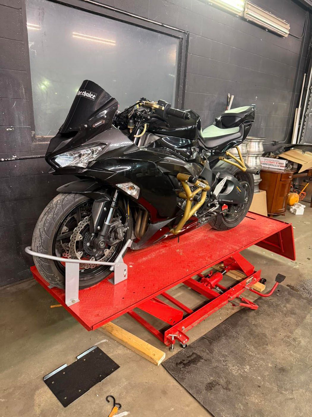 Black sport motorcycle strapped on a red motorcycle lift in a garage workshop