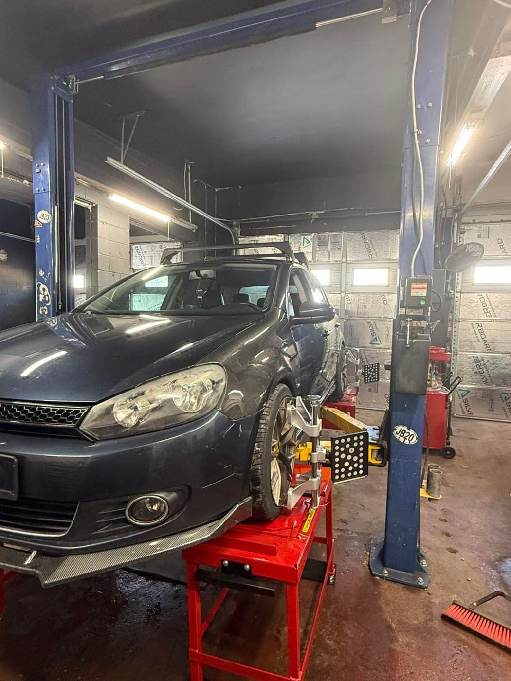 Dark blue car on a lift in an auto repair shop with tools and bright overhead lights