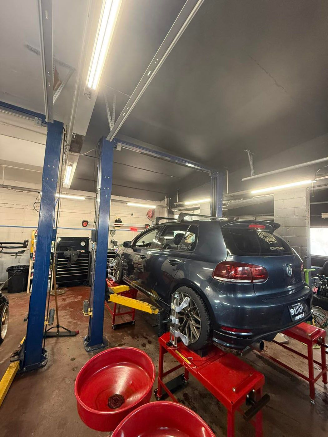 Dark blue car on a red lift in an auto repair garage with blue support columns