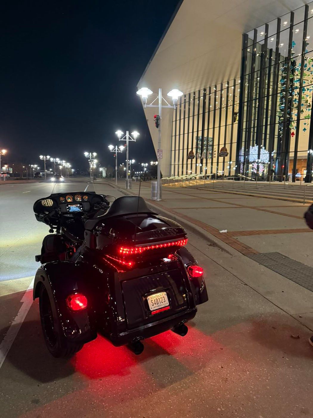 Black motorcycle with red taillights parked at night outside a lit building