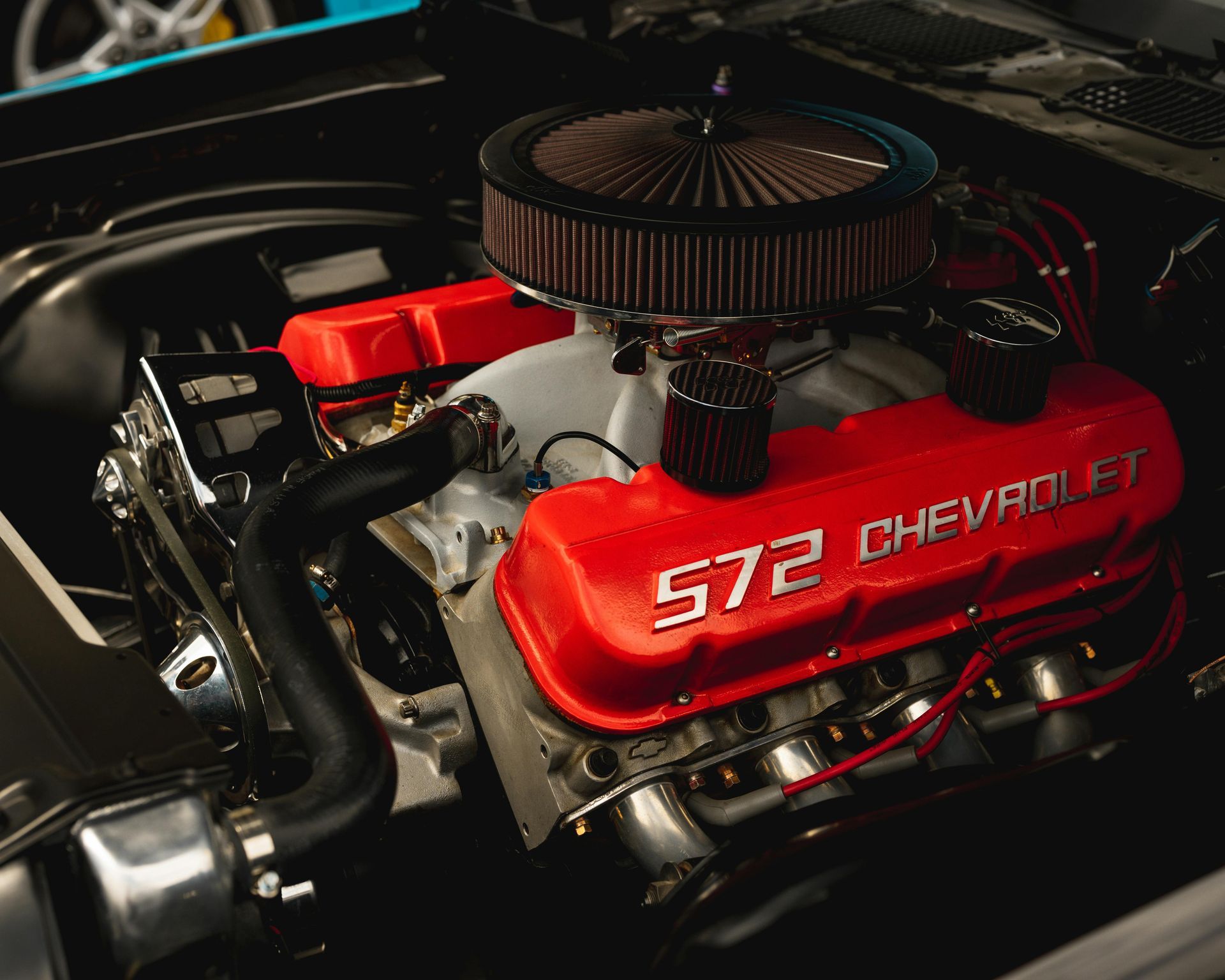 Red Chevrolet 572 engine with chrome air cleaner in a car engine bay
