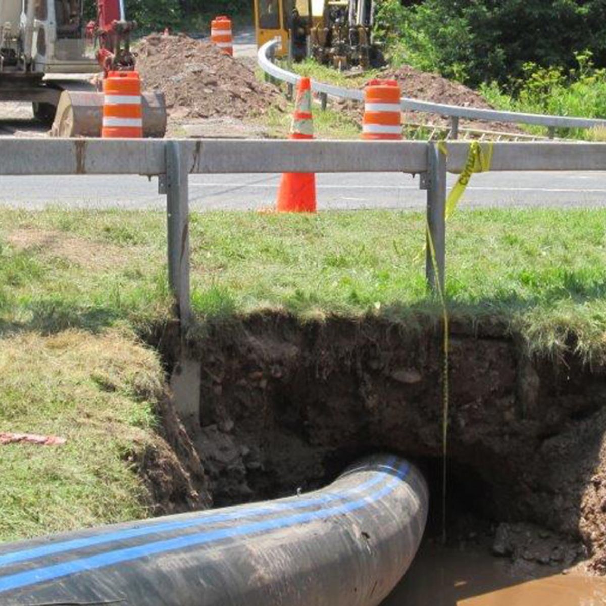 A large pipe is going through a hole in the ground