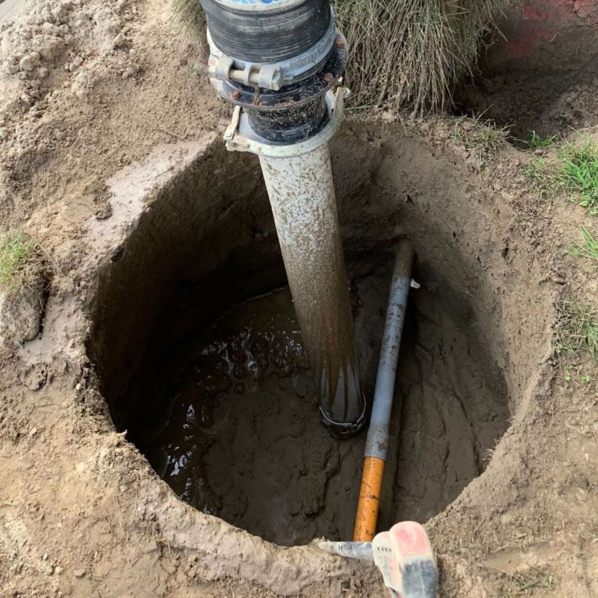 A hose is being pumped into a hole in the ground.