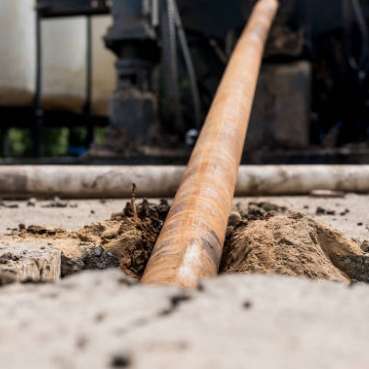 A wooden pipe is sticking out of a hole in the ground.