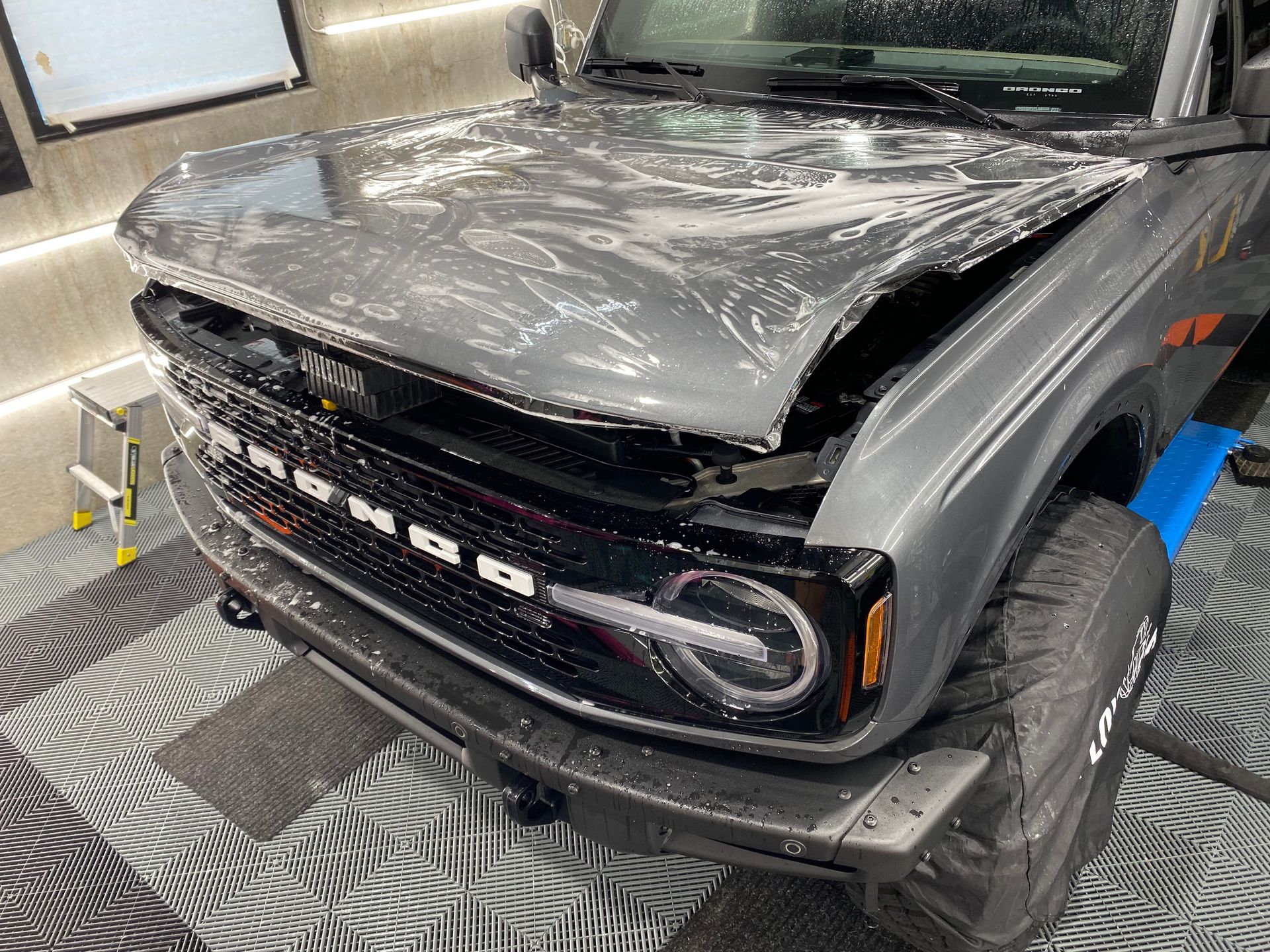 A ford bronco is sitting on a tiled floor in a garage.
