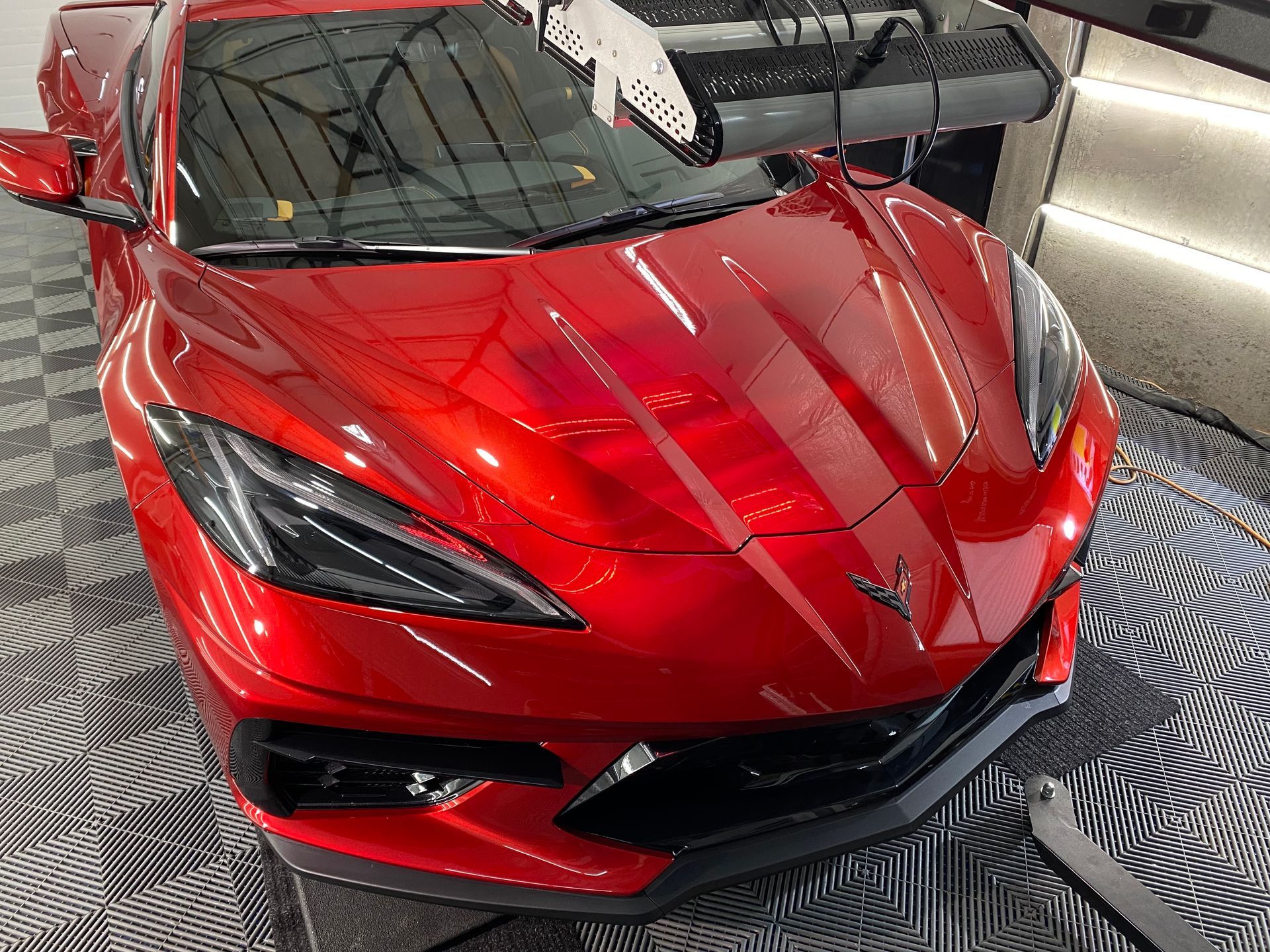 A red sports car is sitting on a checkered floor in a garage.