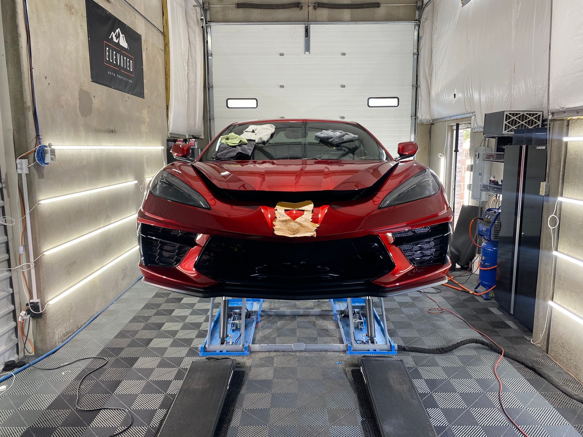A red sports car is parked on a lift in a garage.