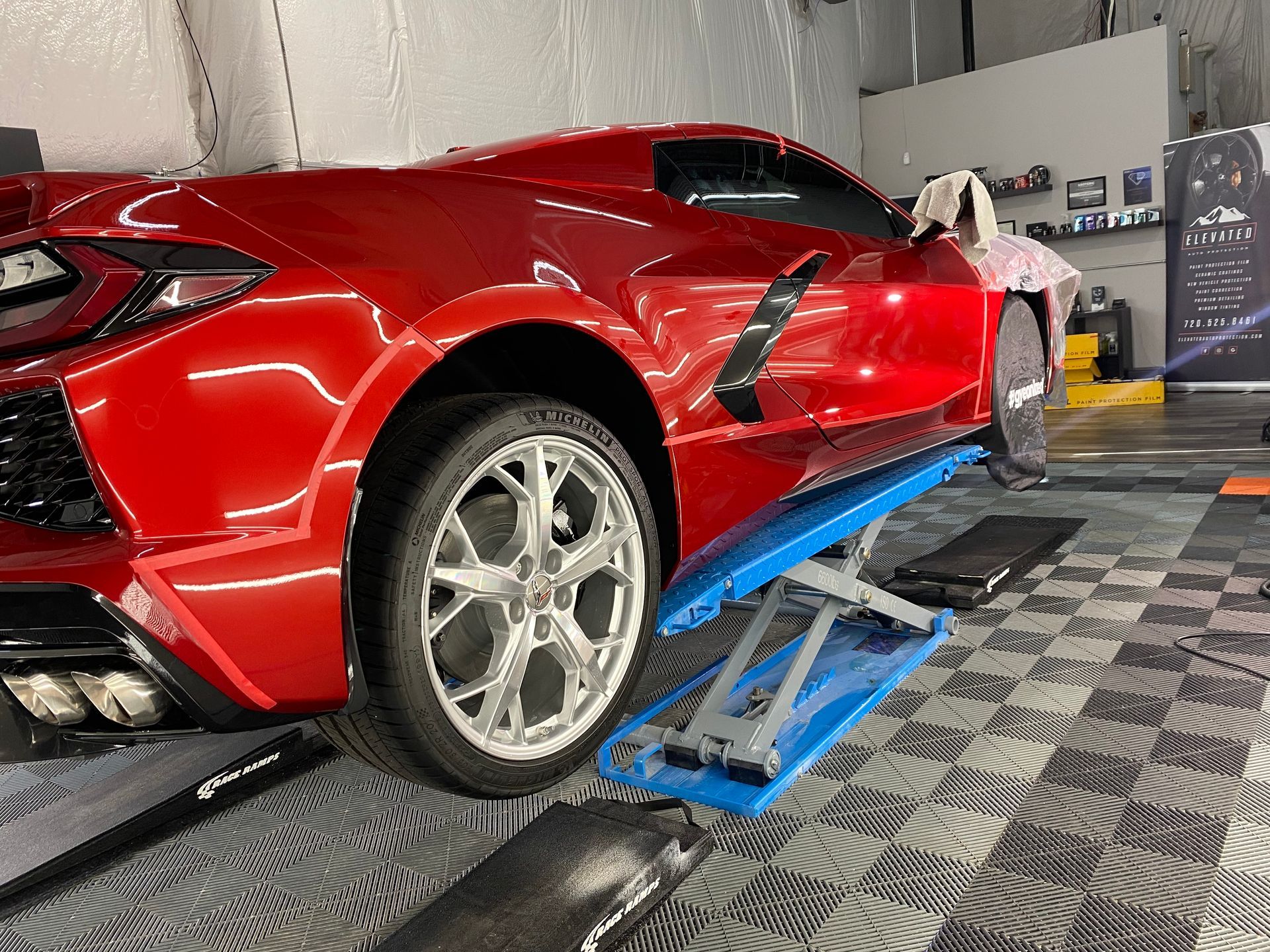 A red sports car is parked on a lift in a garage.