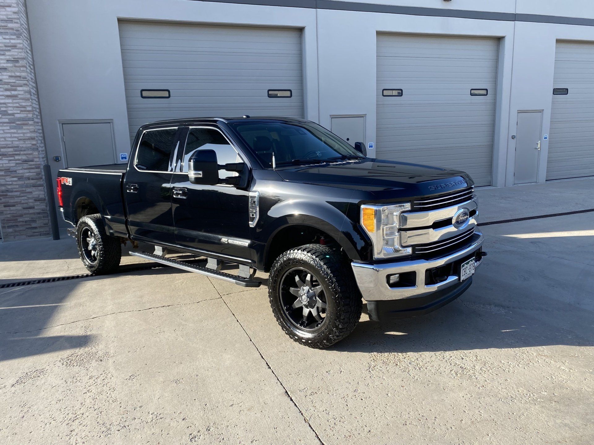 A black ford f250 pickup truck is parked in front of a building.