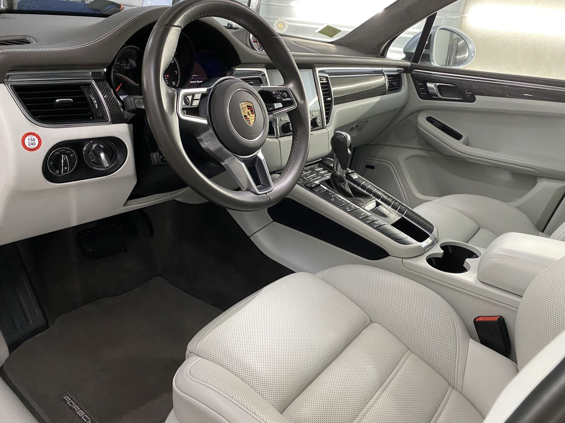 The interior of a porsche macan is shown with white seats and a steering wheel.