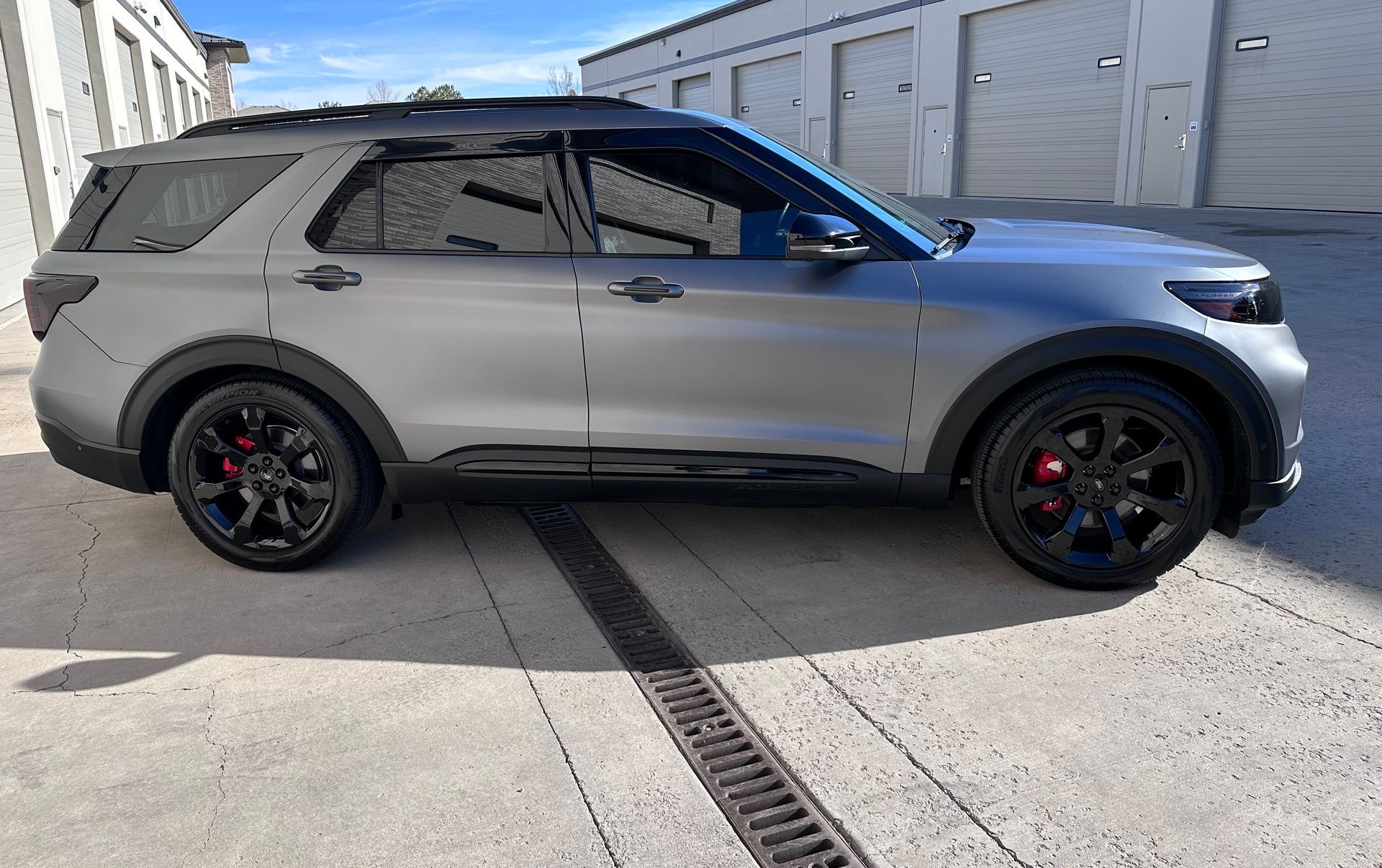 A silver ford explorer is parked in front of a garage.