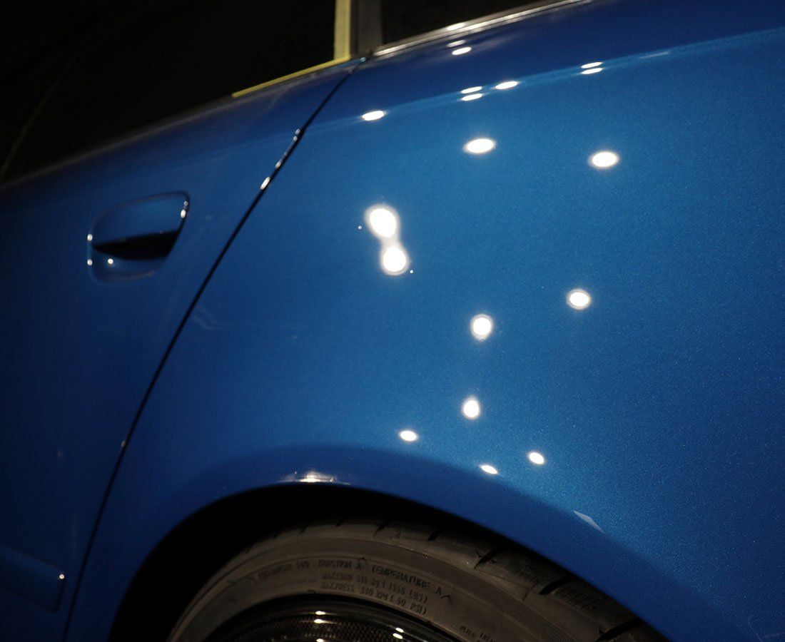 A close up of a blue car with white spots on it