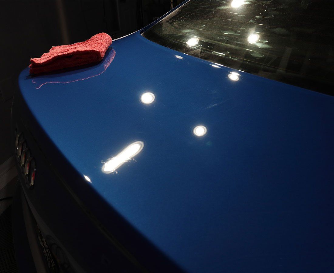 A blue car with a red cloth on the hood