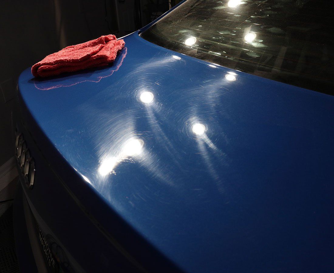 A blue car with a red towel on the hood