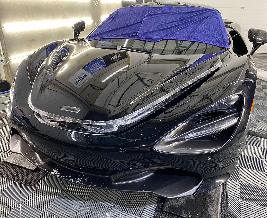 A black sports car with a blue towel on top of it is sitting on a checkered floor.