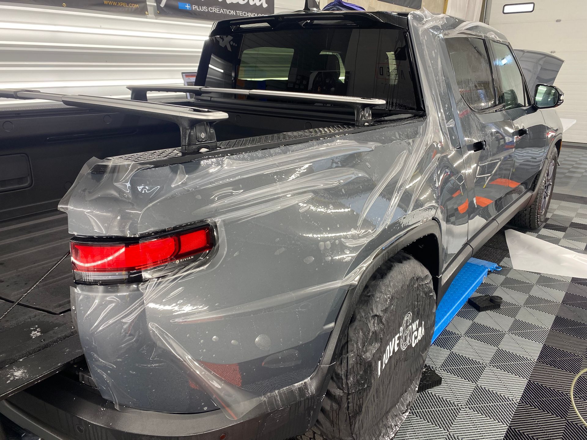 The back of a gray truck is wrapped in plastic.