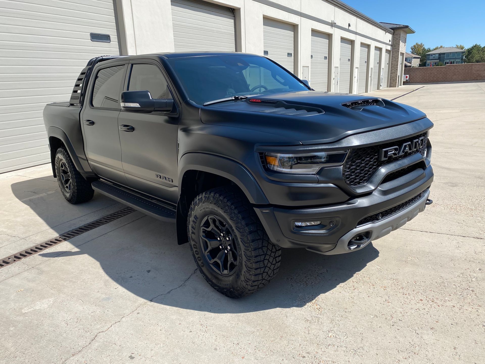 A black dodge ram truck is parked in front of a garage.