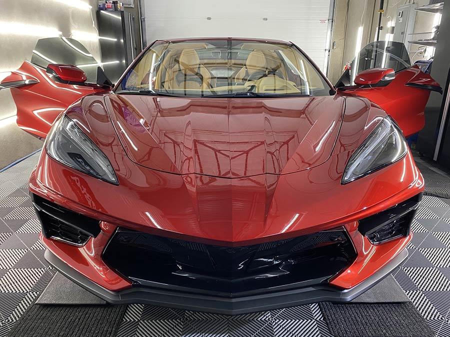 A red sports car is parked in a garage with its doors open.