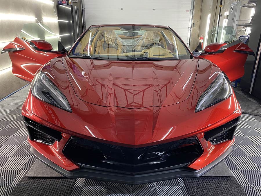 A red sports car is parked in a garage with its doors open.