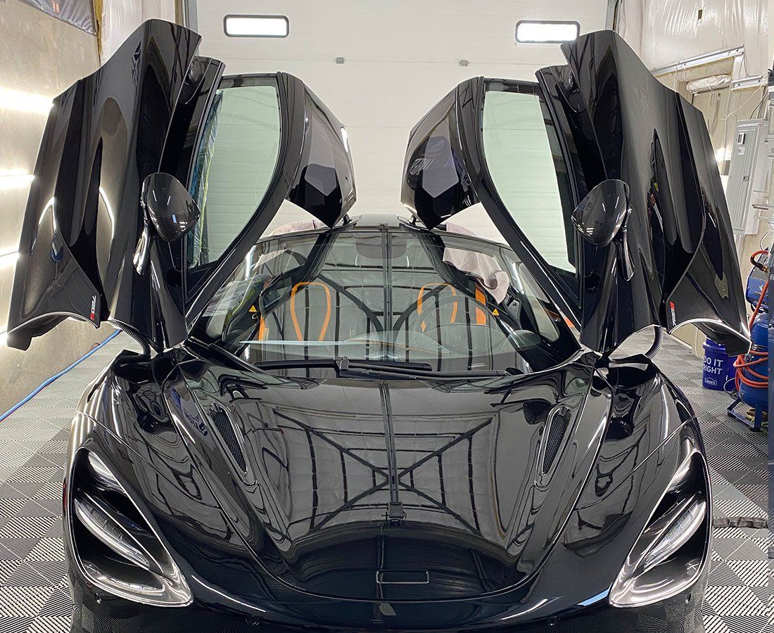 A black sports car with its doors open is parked in a garage.