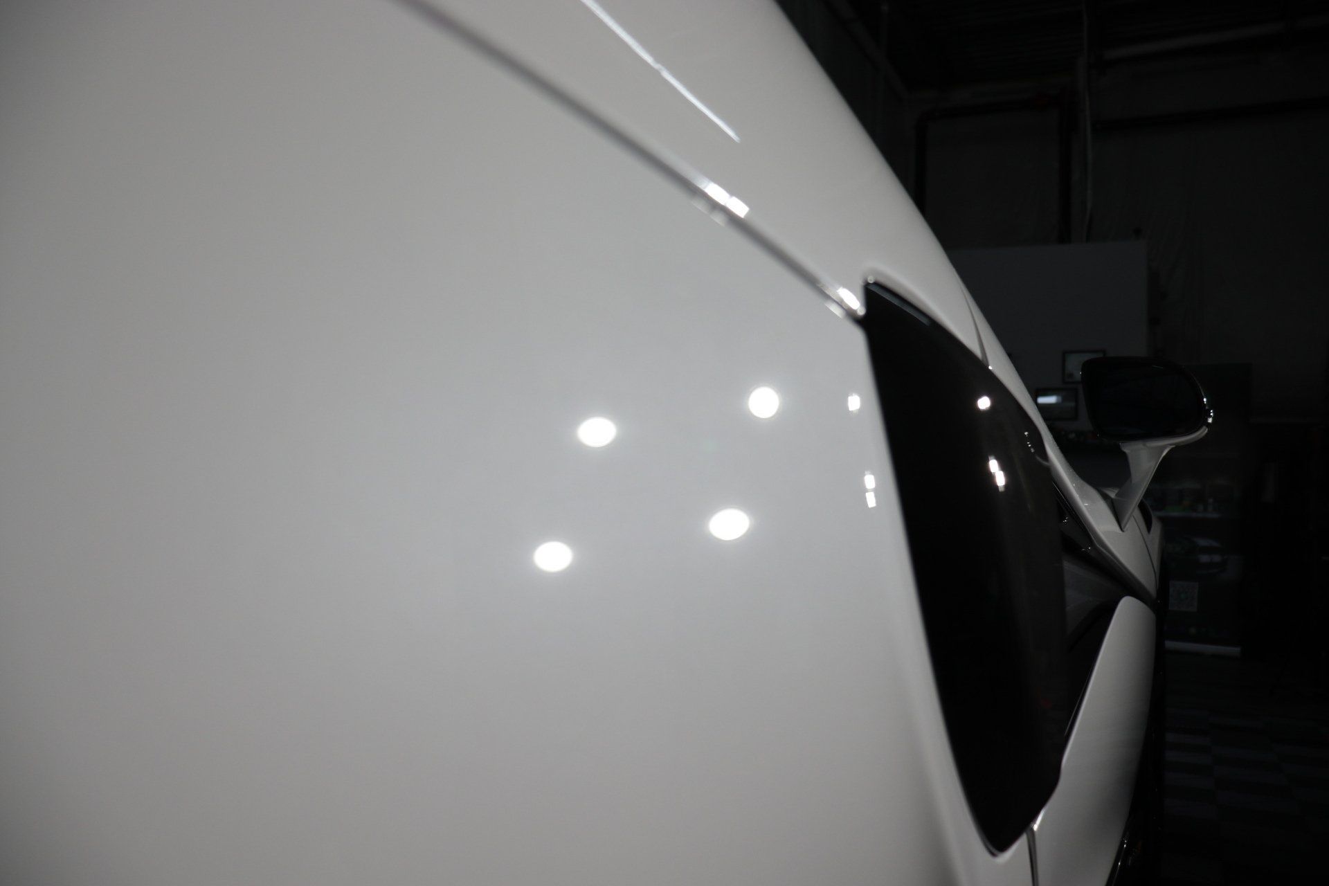 A white car is parked in a dark room