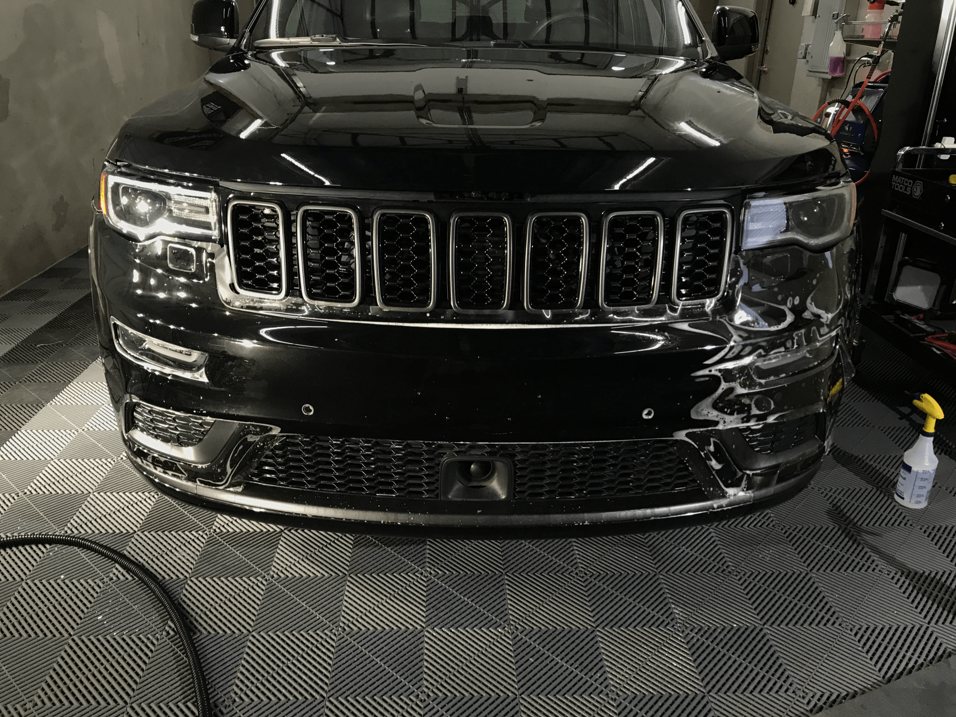 A black jeep grand cherokee is parked in a garage.