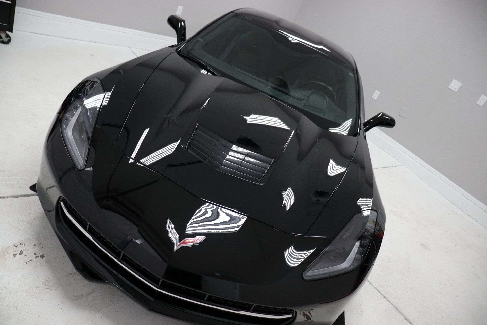 A black sports car is parked in a garage.