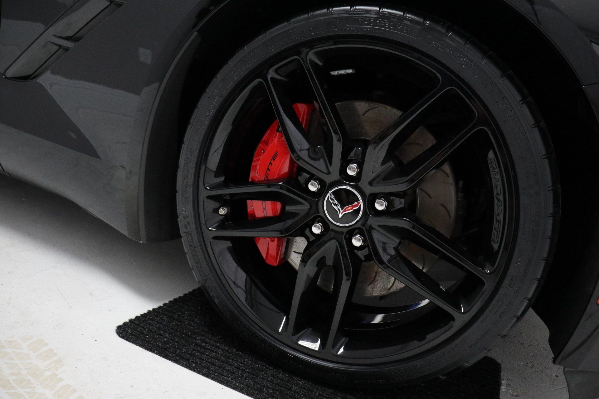 A close up of a black car wheel with red brake calipers.