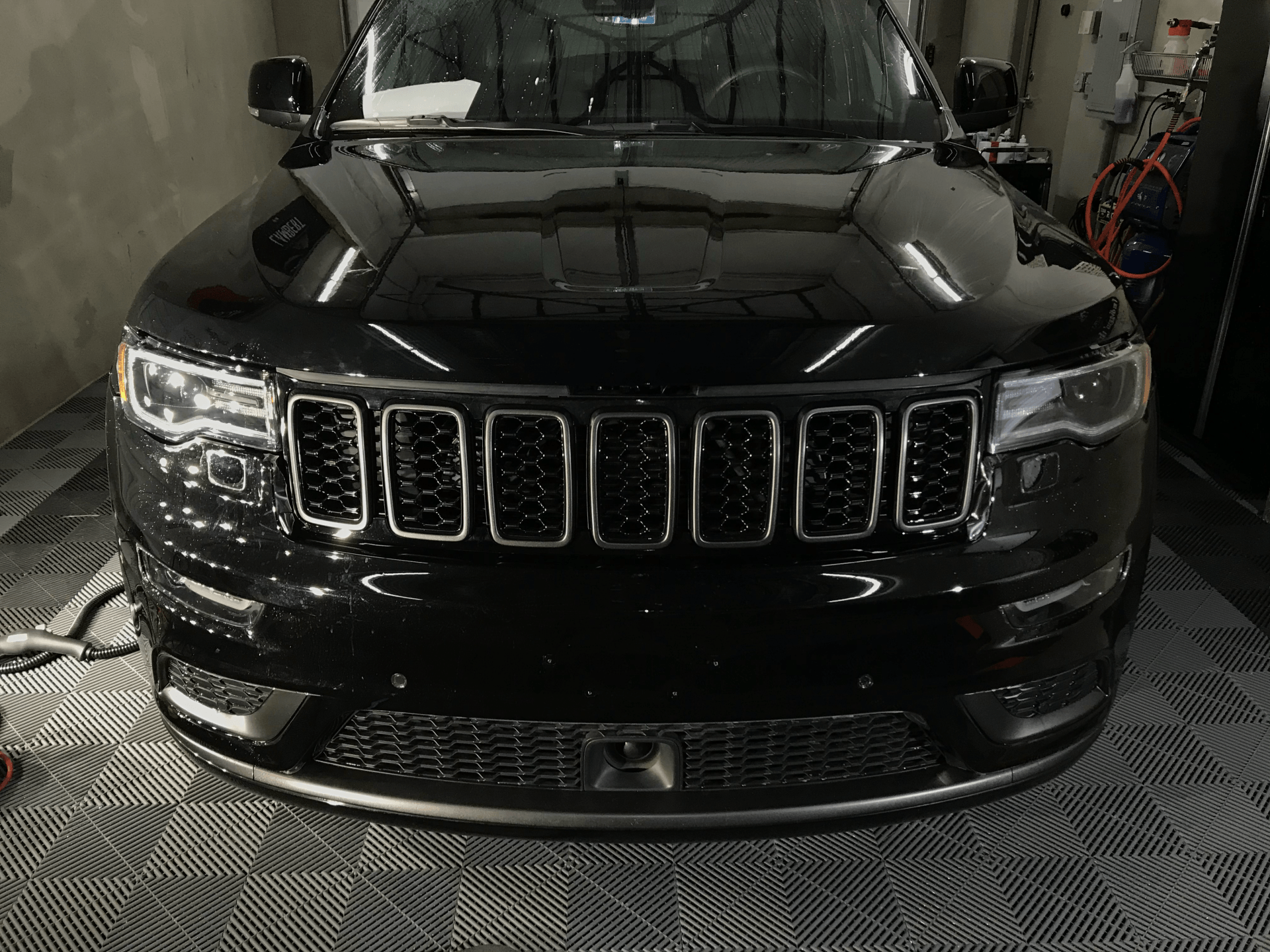 A black jeep grand cherokee is parked in a garage.