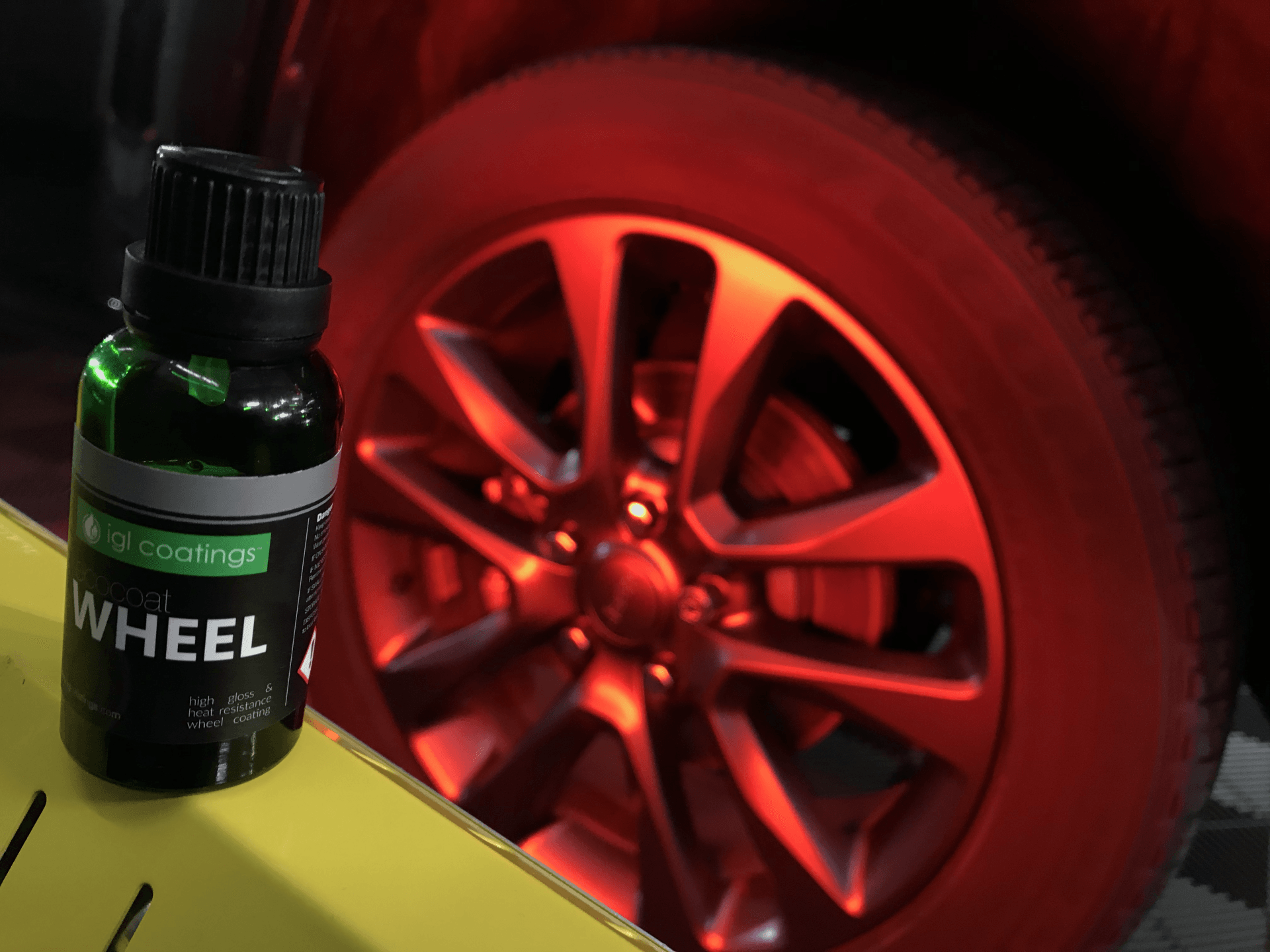 A bottle of wheel paint is sitting next to a car wheel.