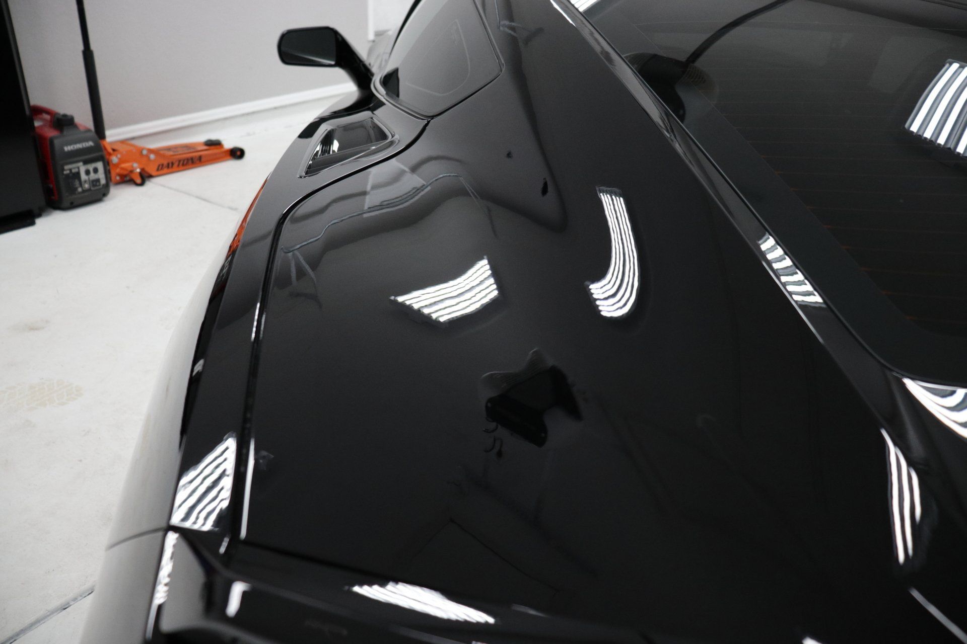 A black sports car is parked in a garage.