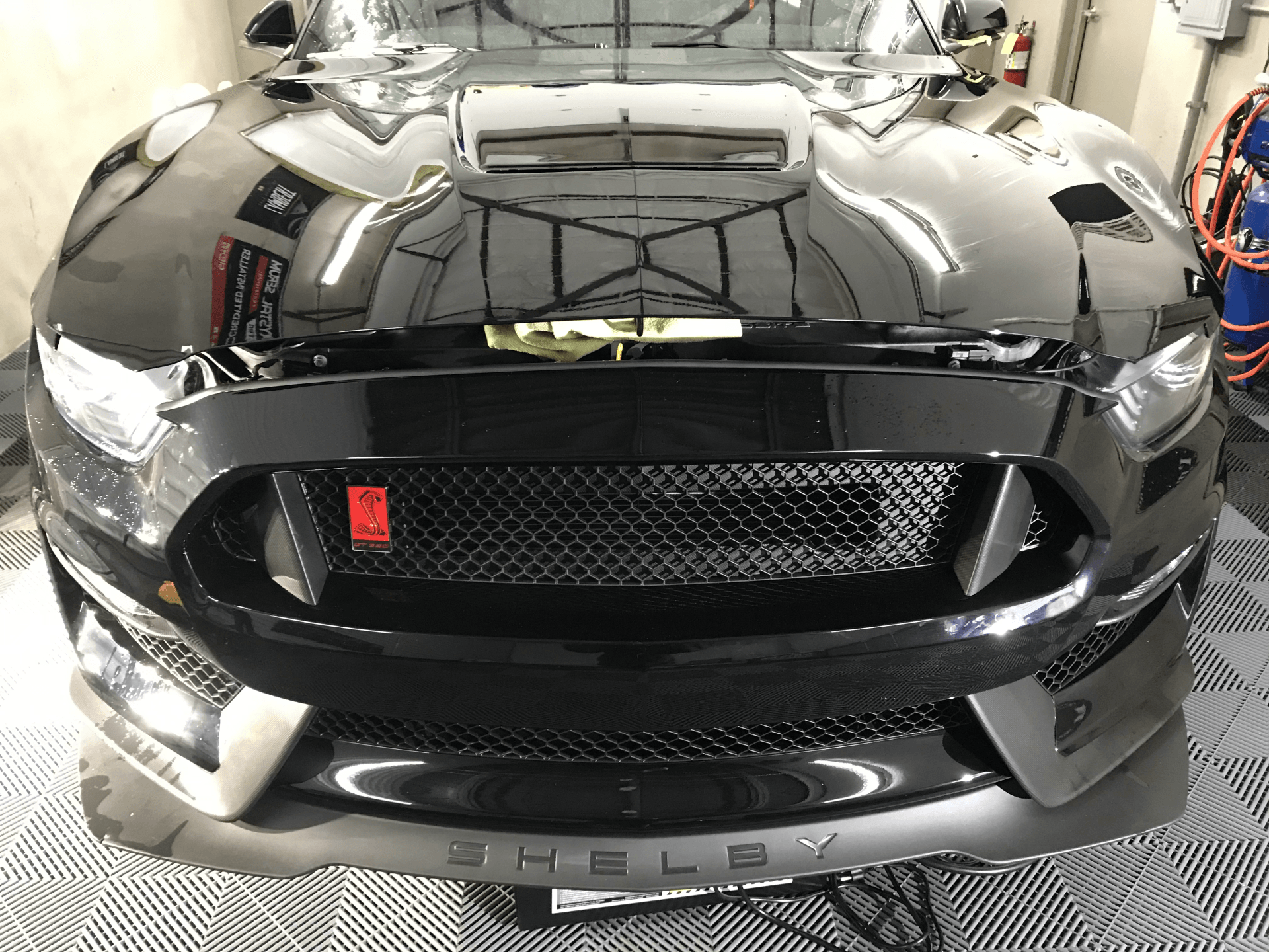 A black ford mustang is parked in a garage.