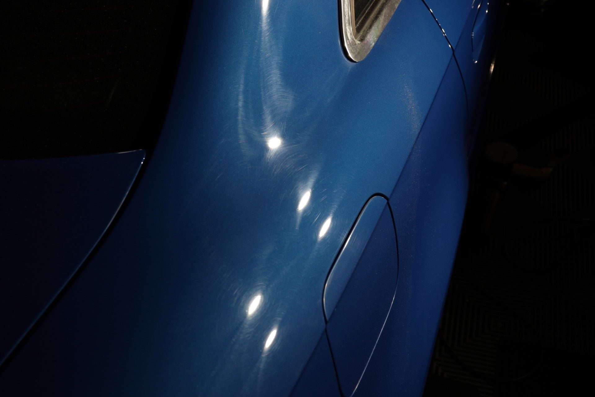 A close up of a blue car with a black background.