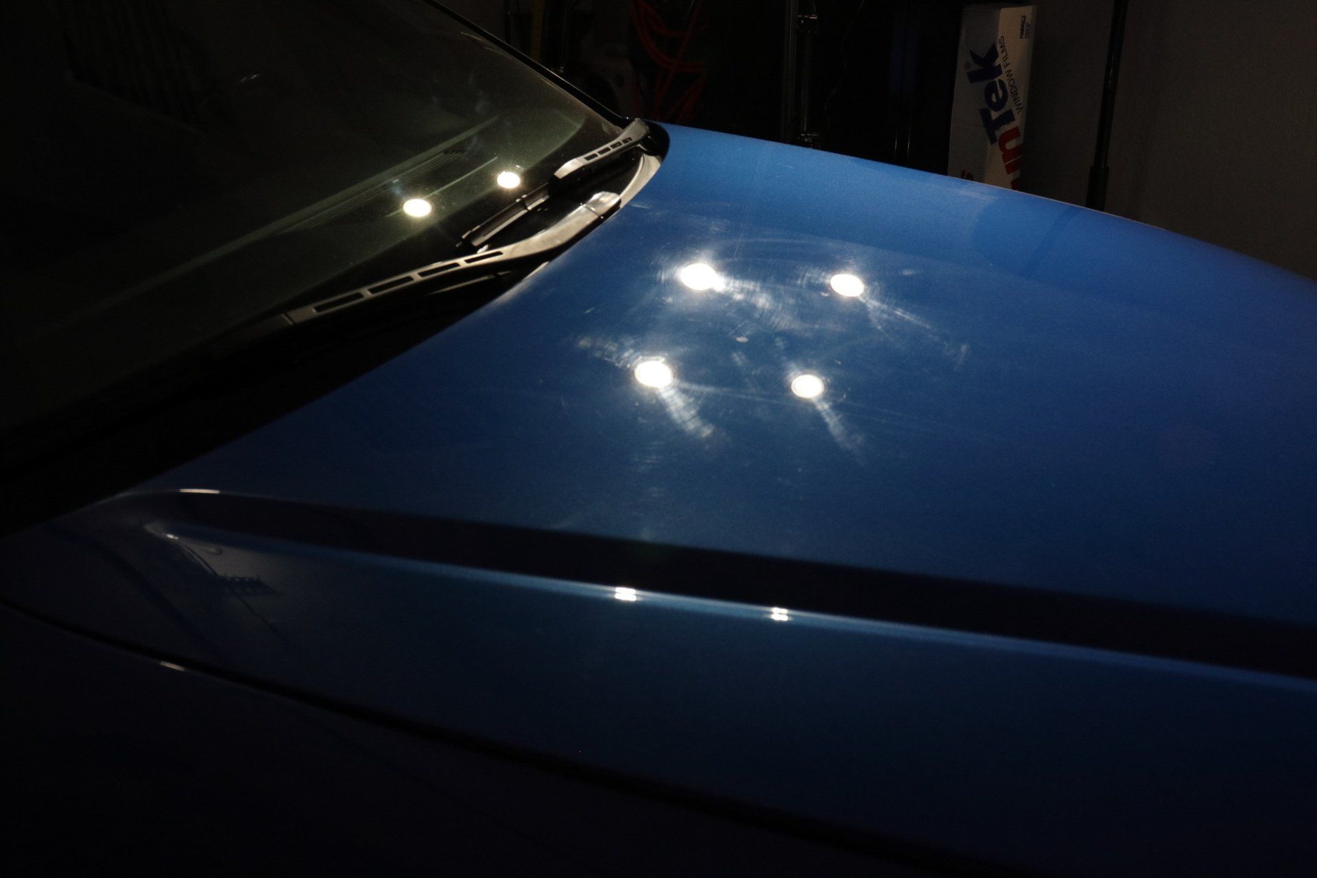 A close up of a blue car 's hood and windshield