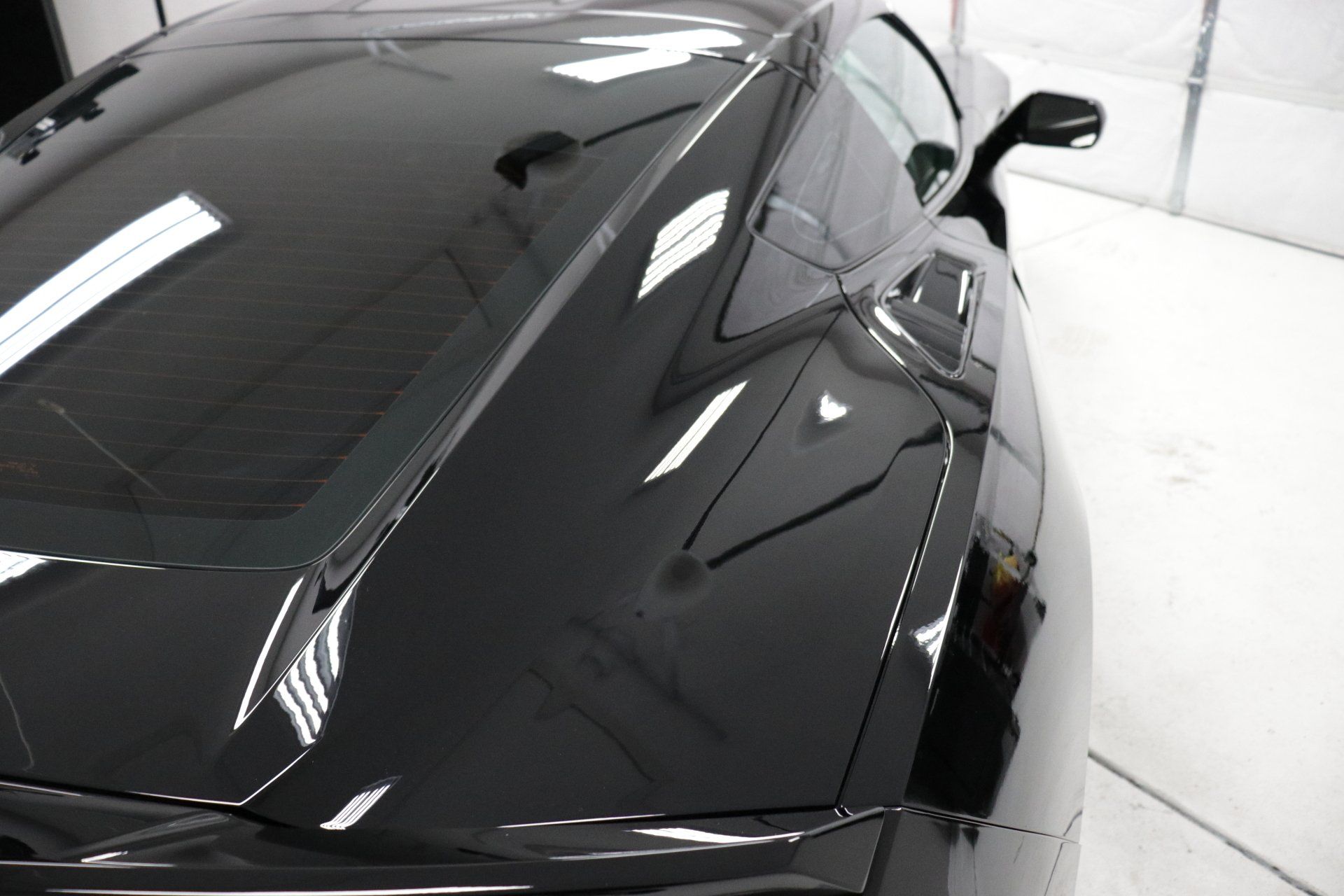 A black sports car is parked in a garage.