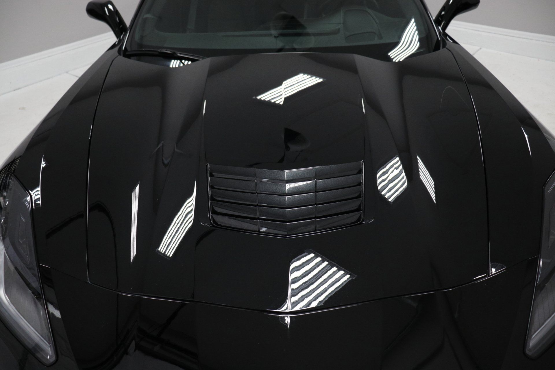A close up of a black car 's hood and headlights