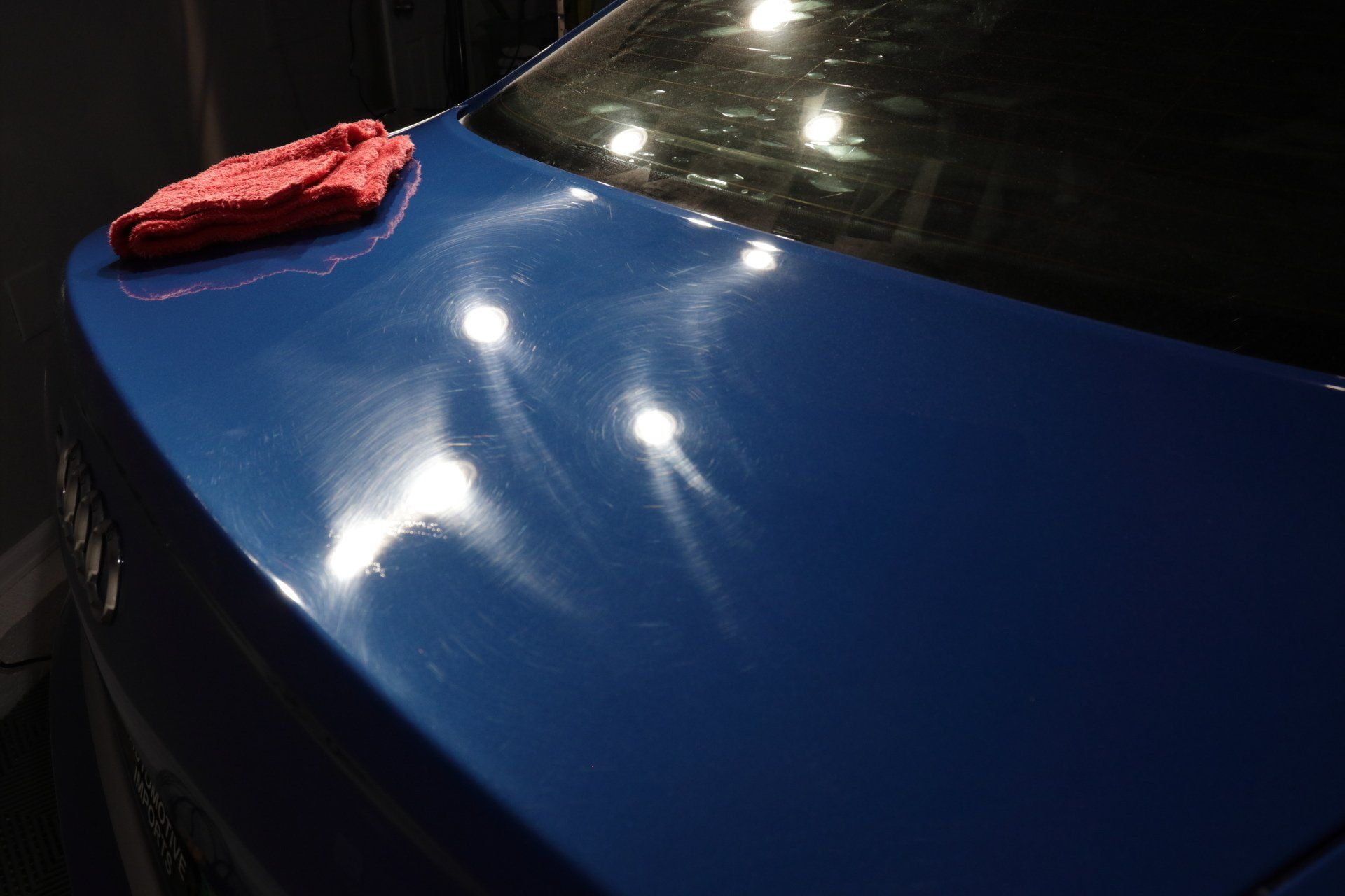 A blue car with a red towel on the hood.