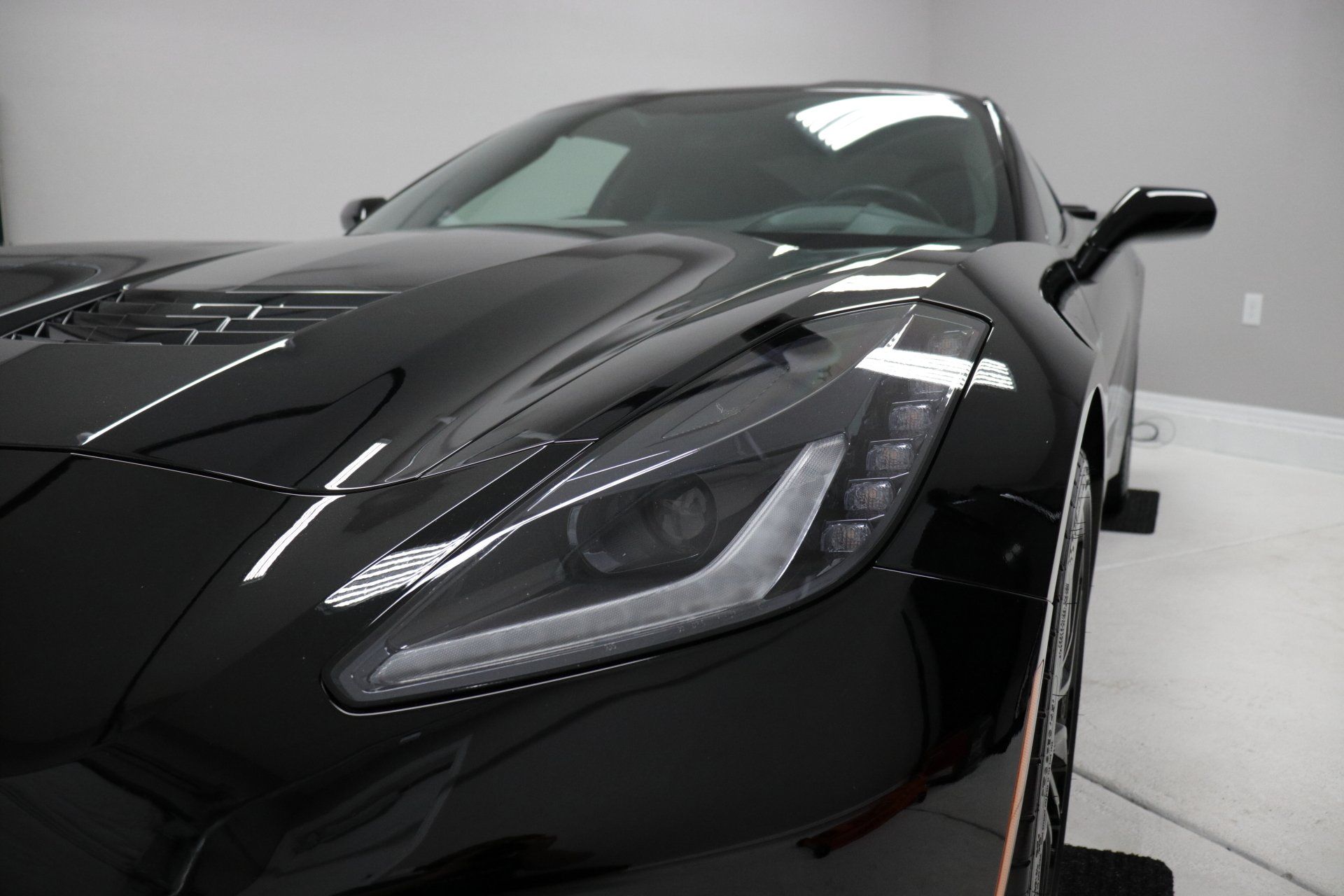A black sports car is parked in a garage.