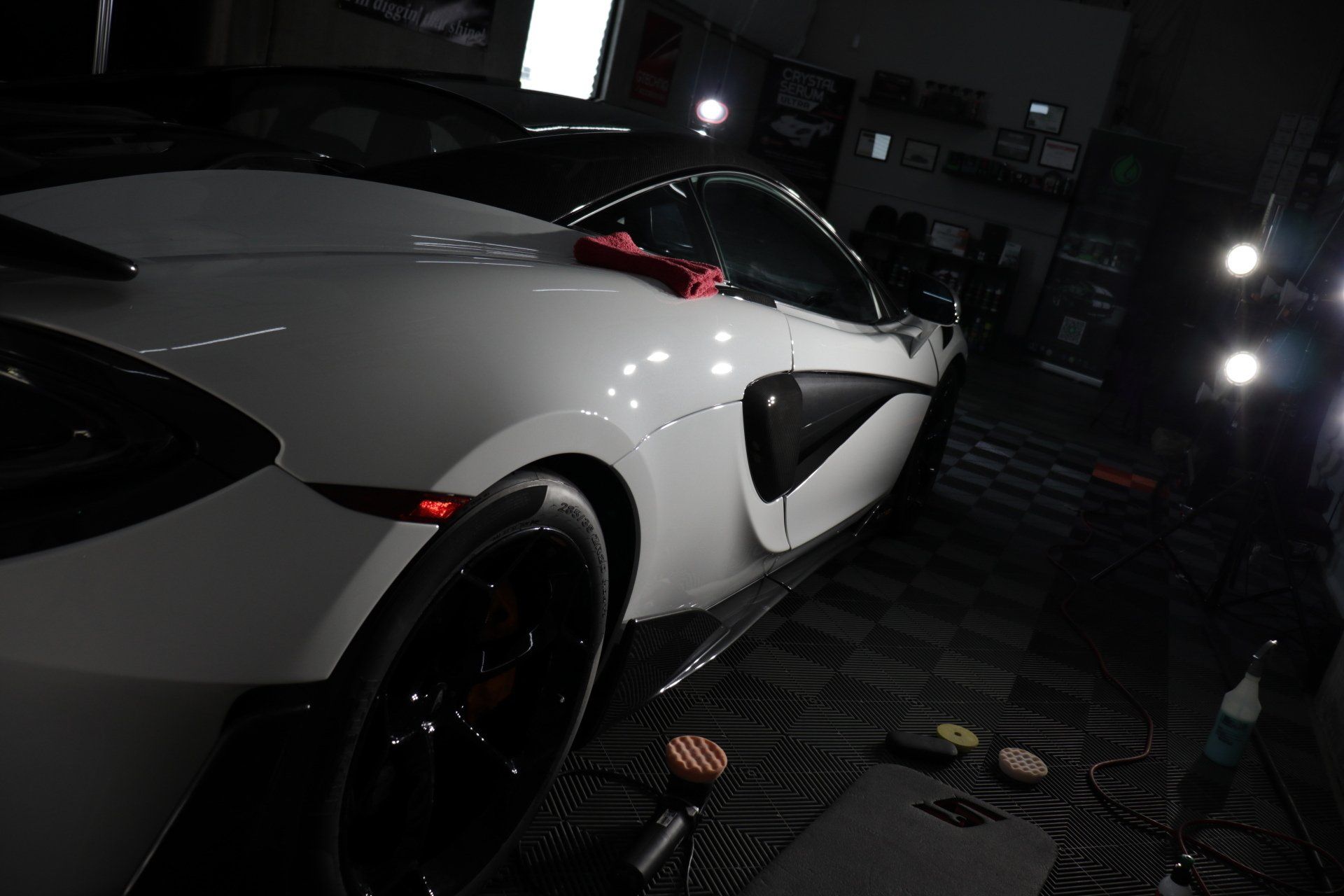 A white sports car is parked in a dark room.