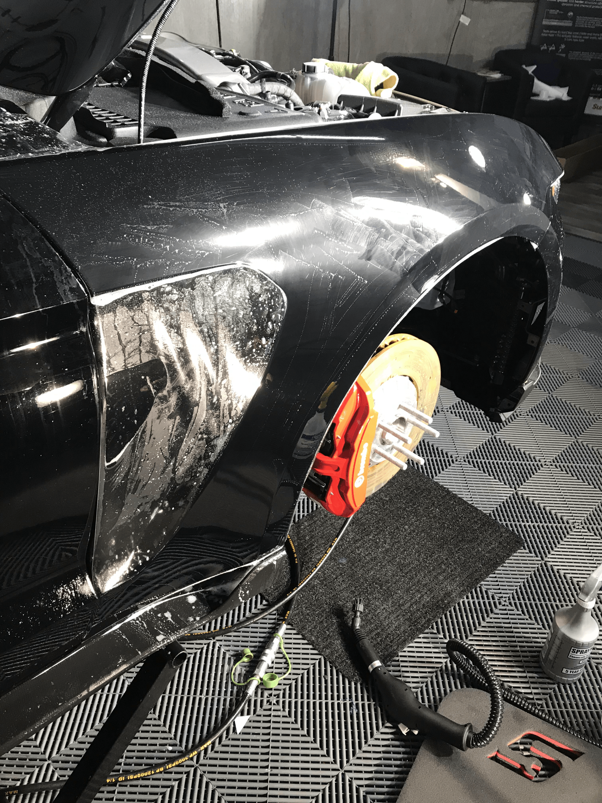 A black car is sitting on a lift with the hood open