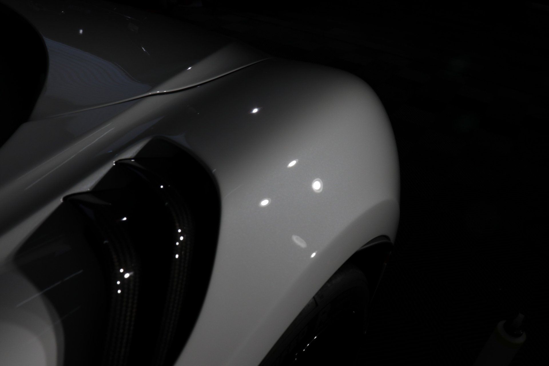 A close up of a white car 's fender in the dark.