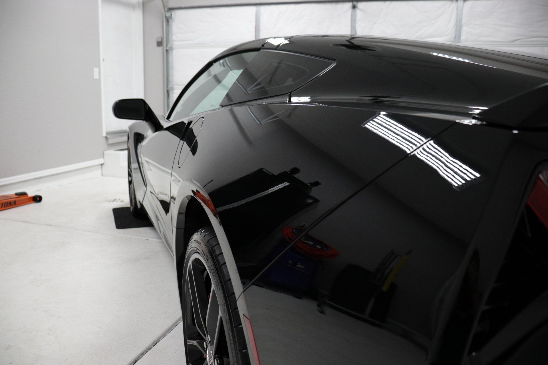 A black sports car is parked in a garage.