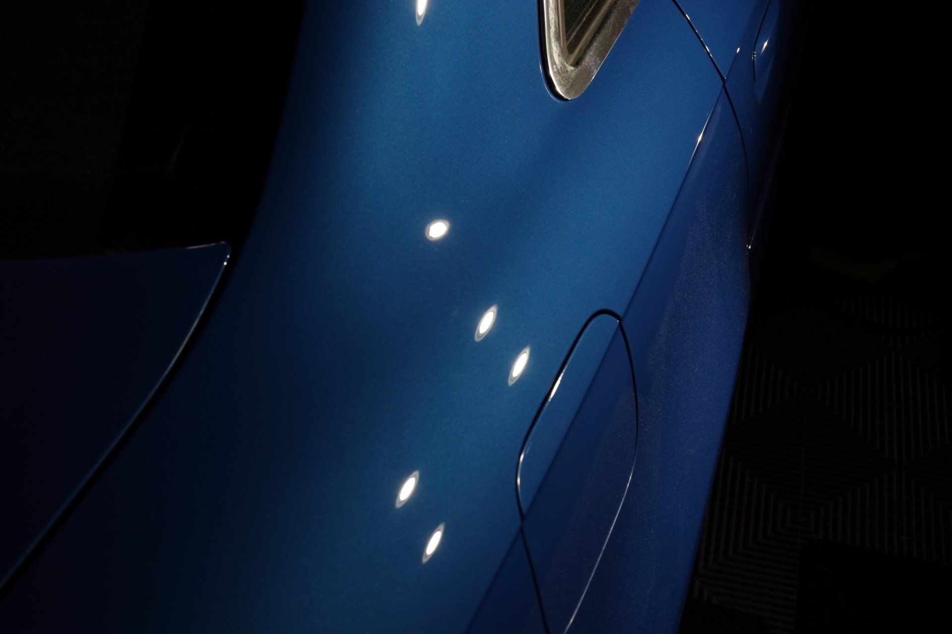 A close up of a blue car with white spots on it.