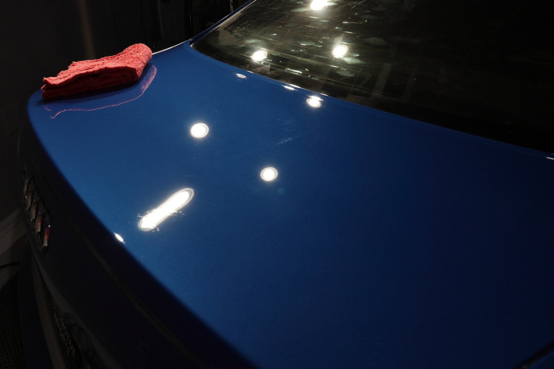 A blue car with a red cloth on the hood