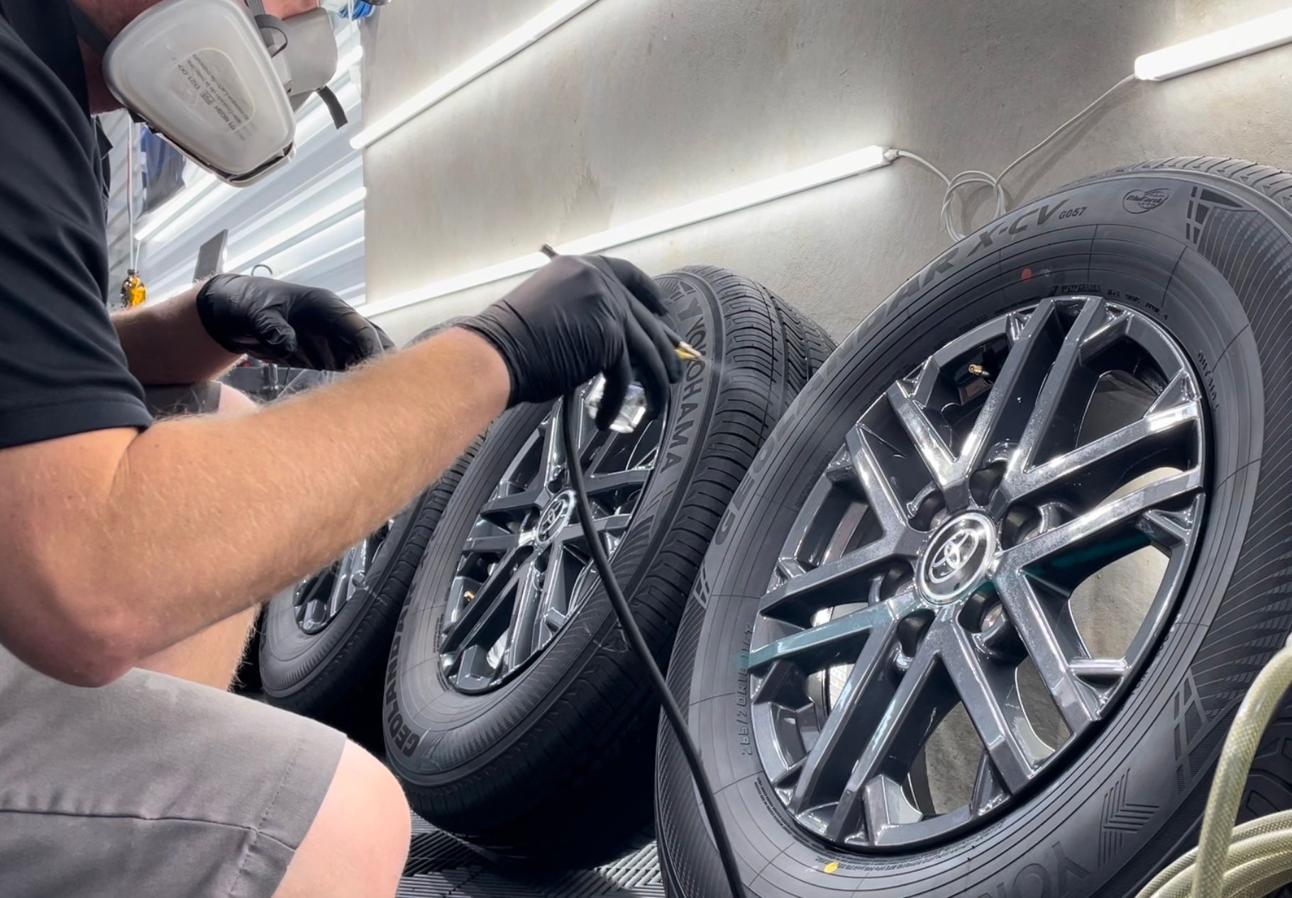 A man wearing a mask is working on a stack of tires.