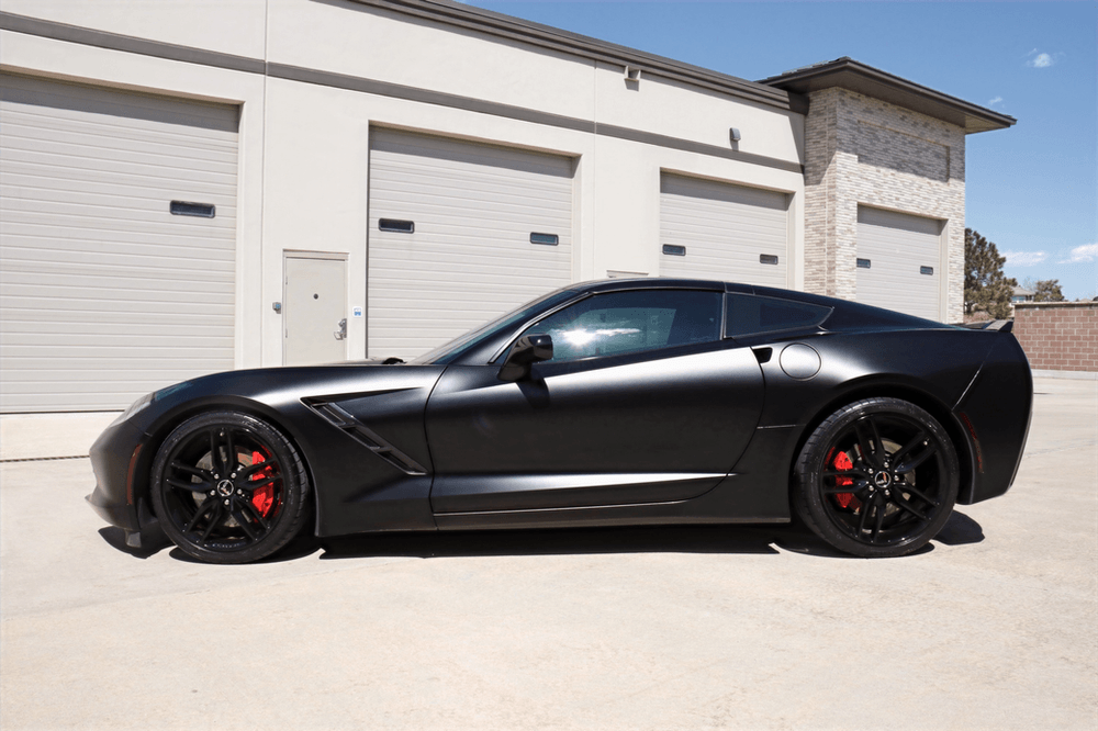 A black sports car is parked in front of a garage.