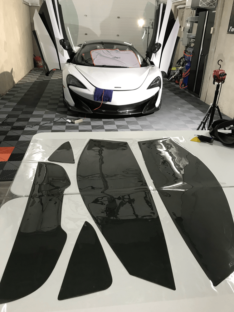 A white sports car is parked in a garage with its doors open.