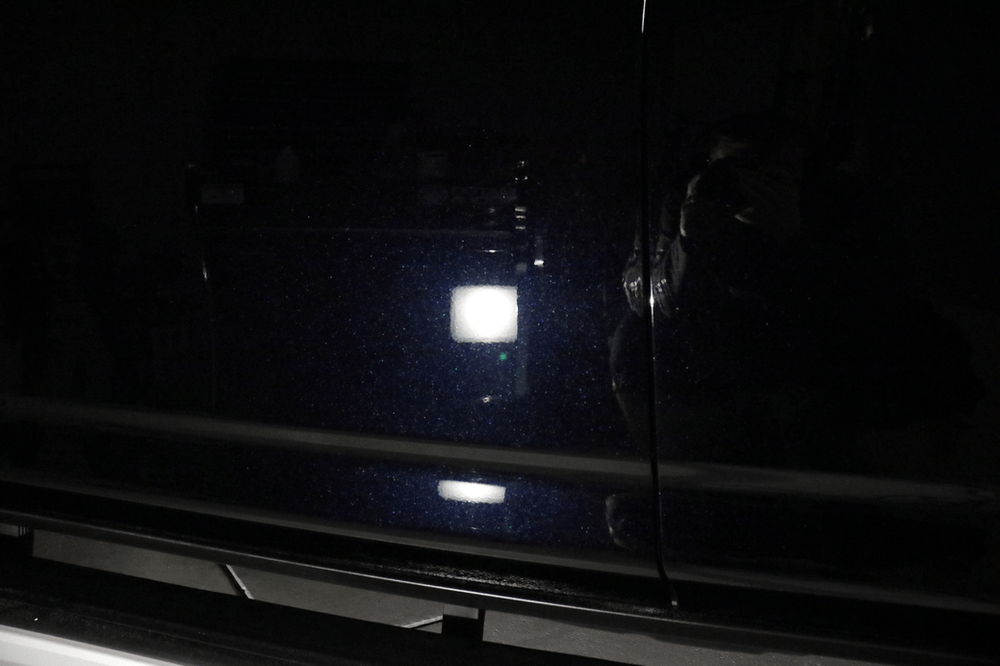 A close up of a car door with a light on it in the dark.